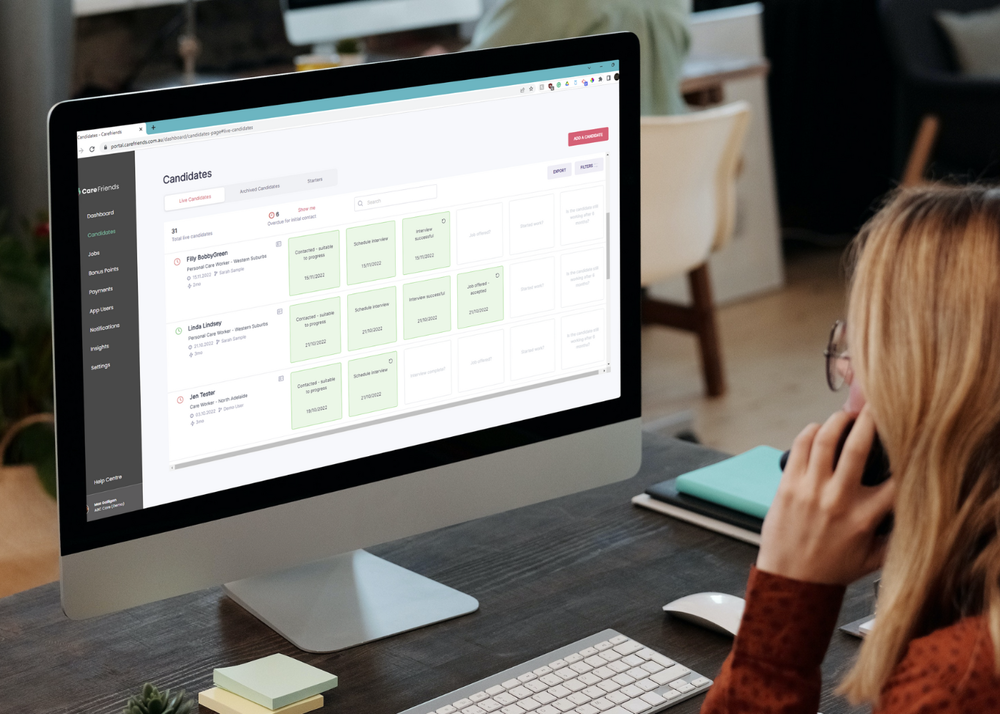 Computer on desk with person on phone